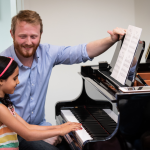 A piano teacher at Musicians Playground helping his young student through a difficult passage.