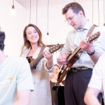 Two Adults Playing Guitar In A Group